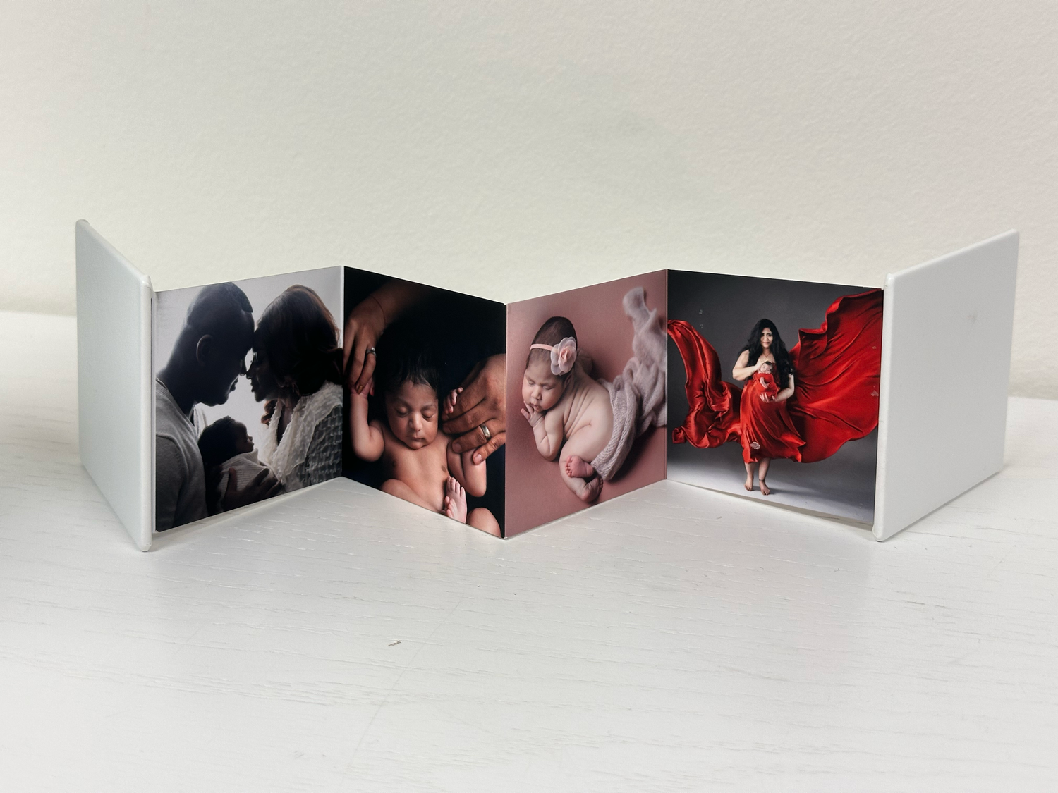 Accordion-style photo book displaying three professional portraits including maternity and newborn photography sessions.