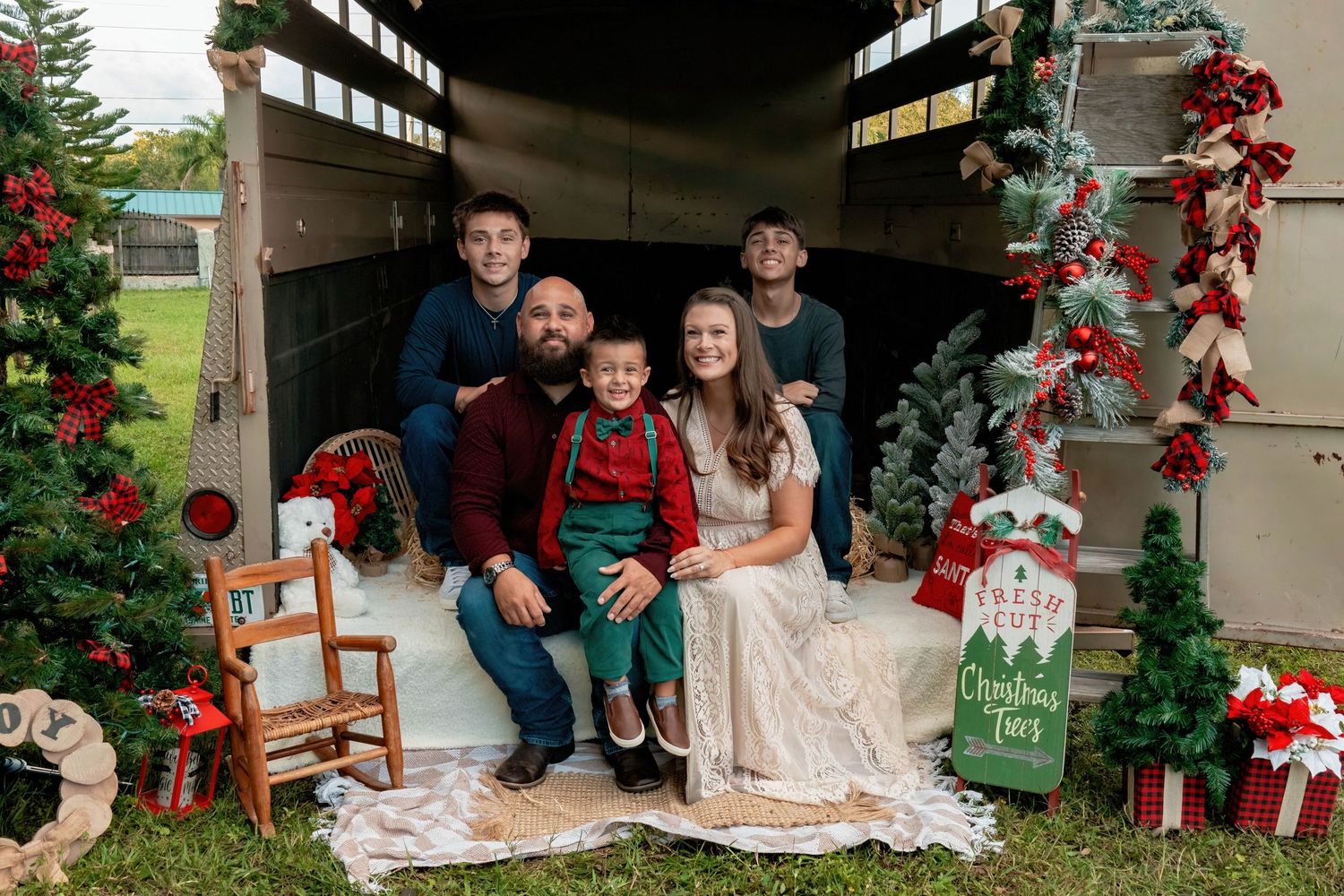 Family Christmas photo session with rustic wood backdrop and holiday decorations.