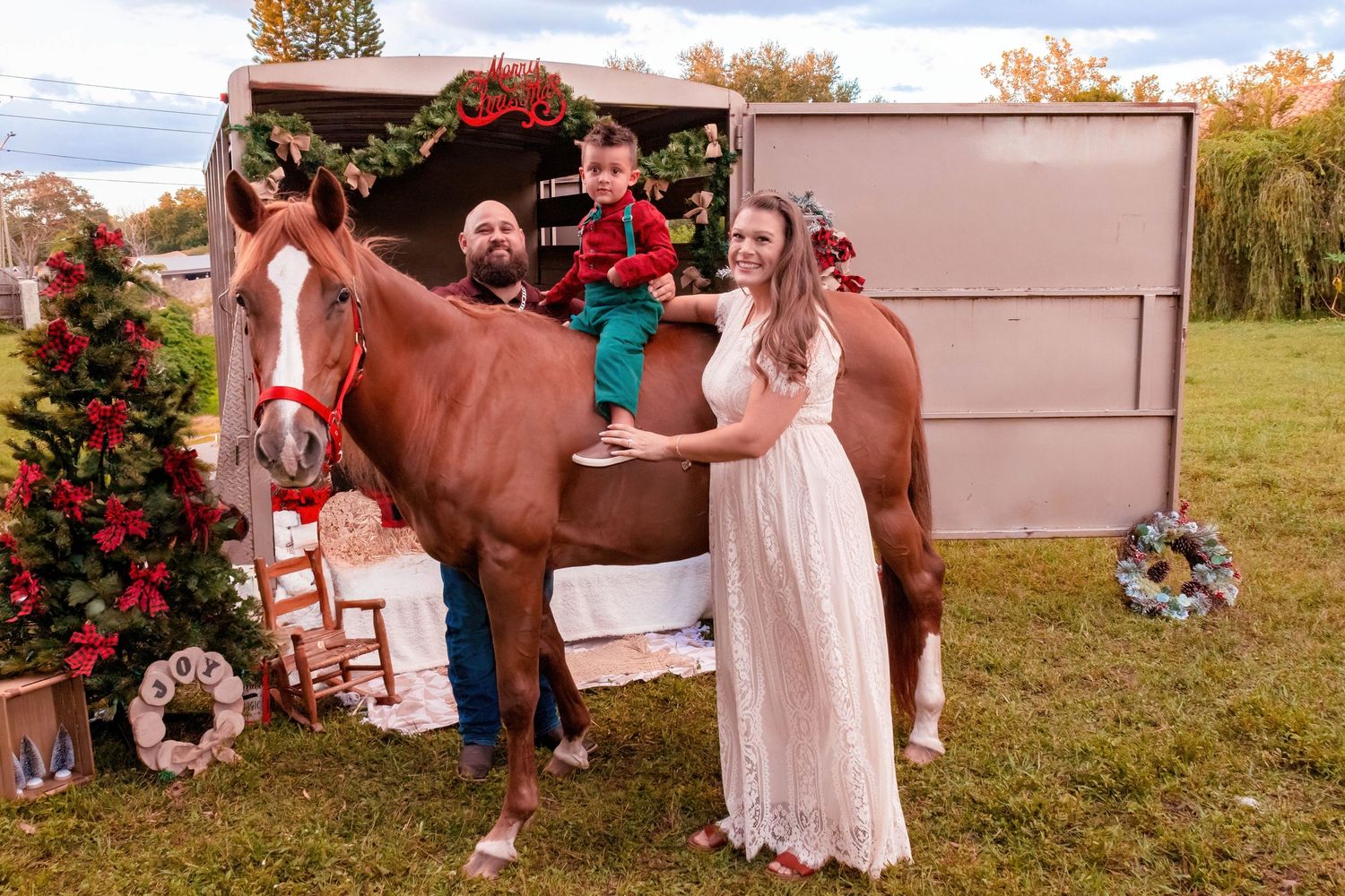 Holiday photoshoot setup with brown horse and festive decorations in a rustic outdoor setting.