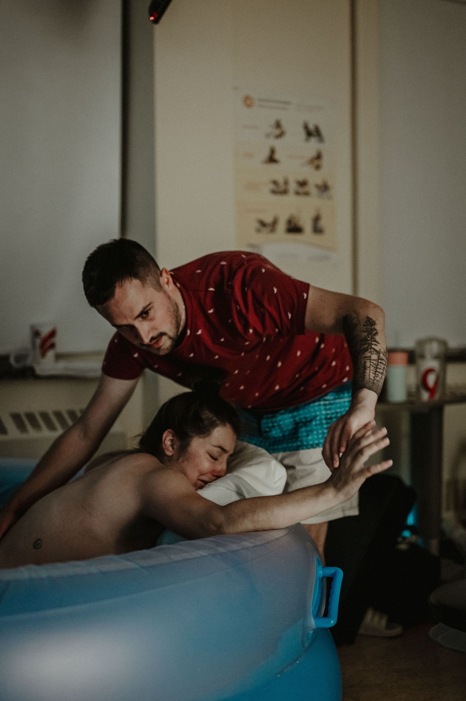 A massage therapist in a red polka dot shirt performs therapeutic treatment on a client in a medical office setting.