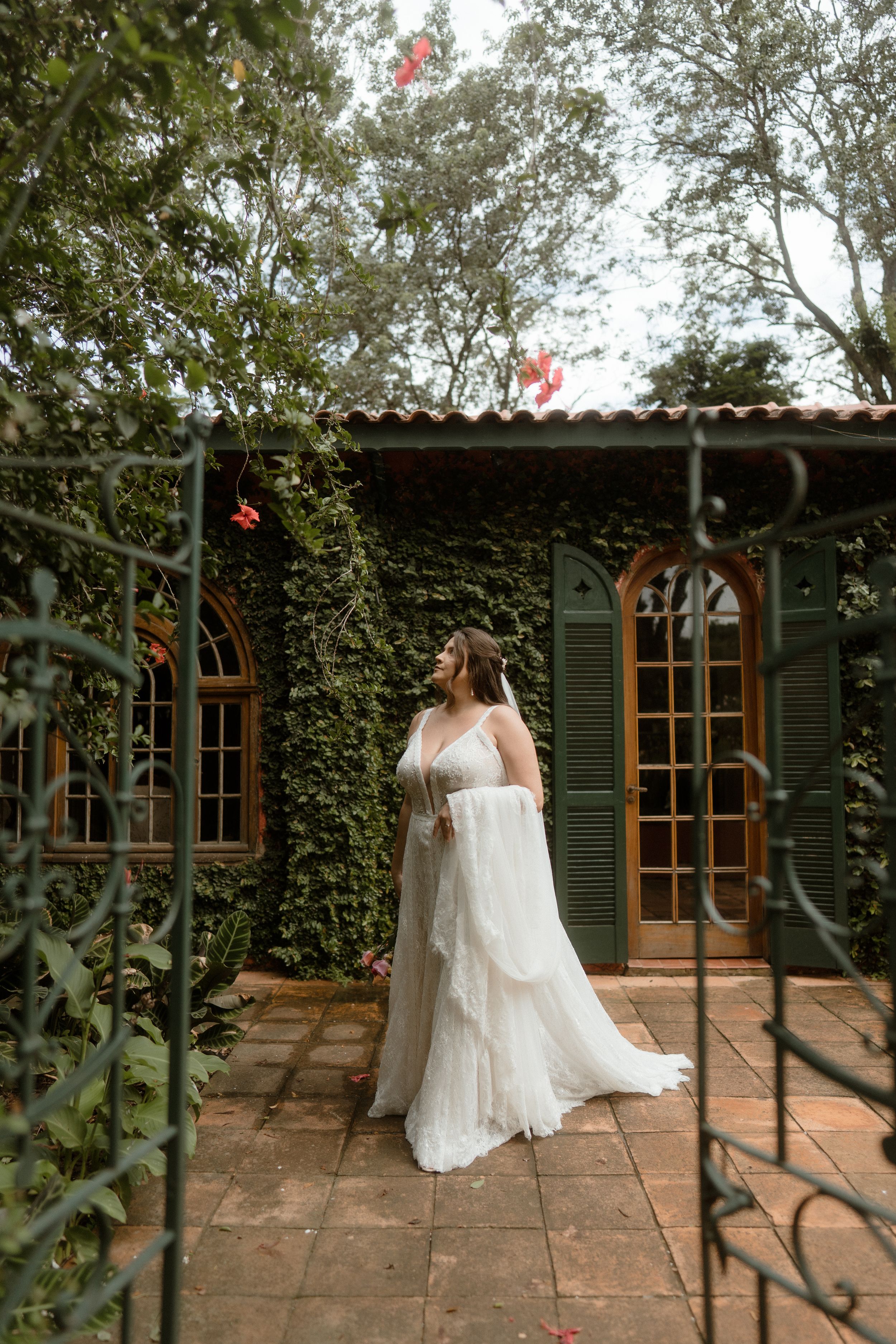 Wedding dress portrait in garden setting with ivy-covered walls and iron gates.