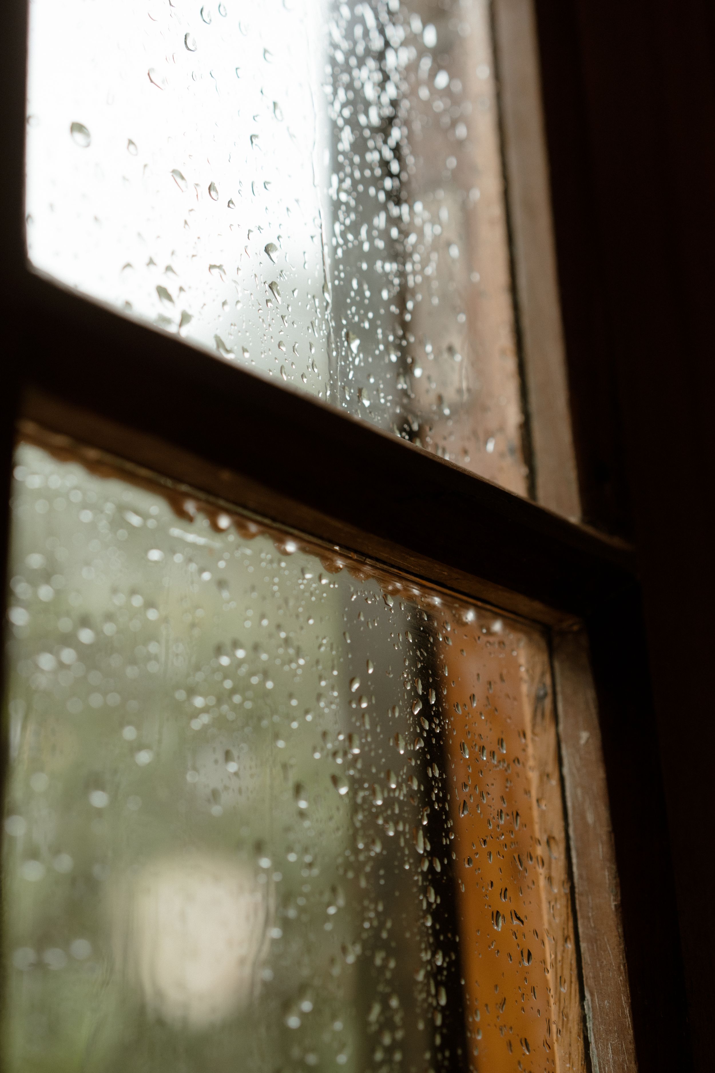 Raindrops on a window pane create a dreamy, moody atmosphere.