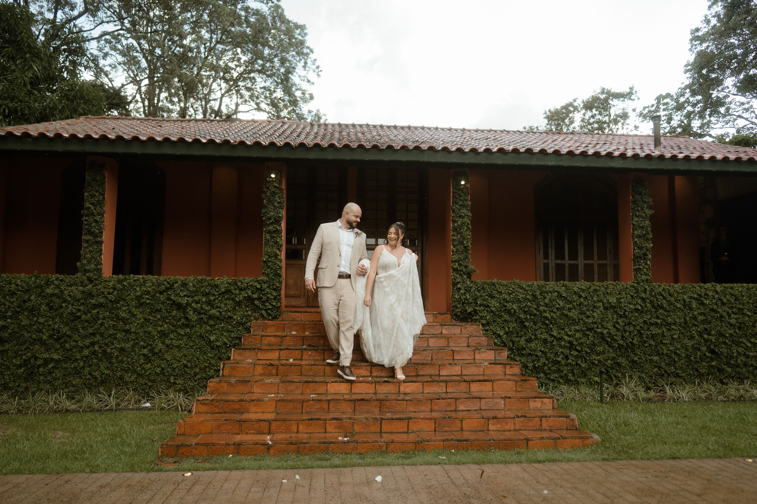 Newlyweds descending terracotta steps of rustic hacienda-style building.