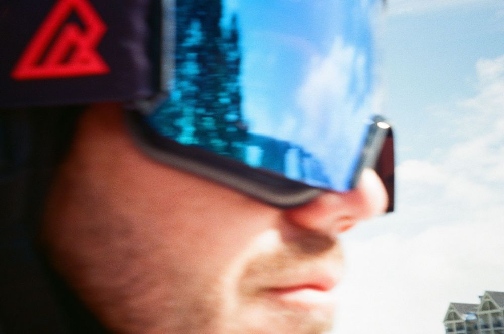 Close-up view of someone wearing reflective blue sports sunglasses against a bright sky background.