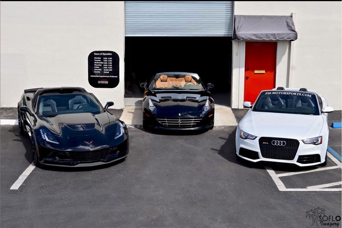Three luxury sports cars including an Audi and other high-end vehicles parked in a garage.
