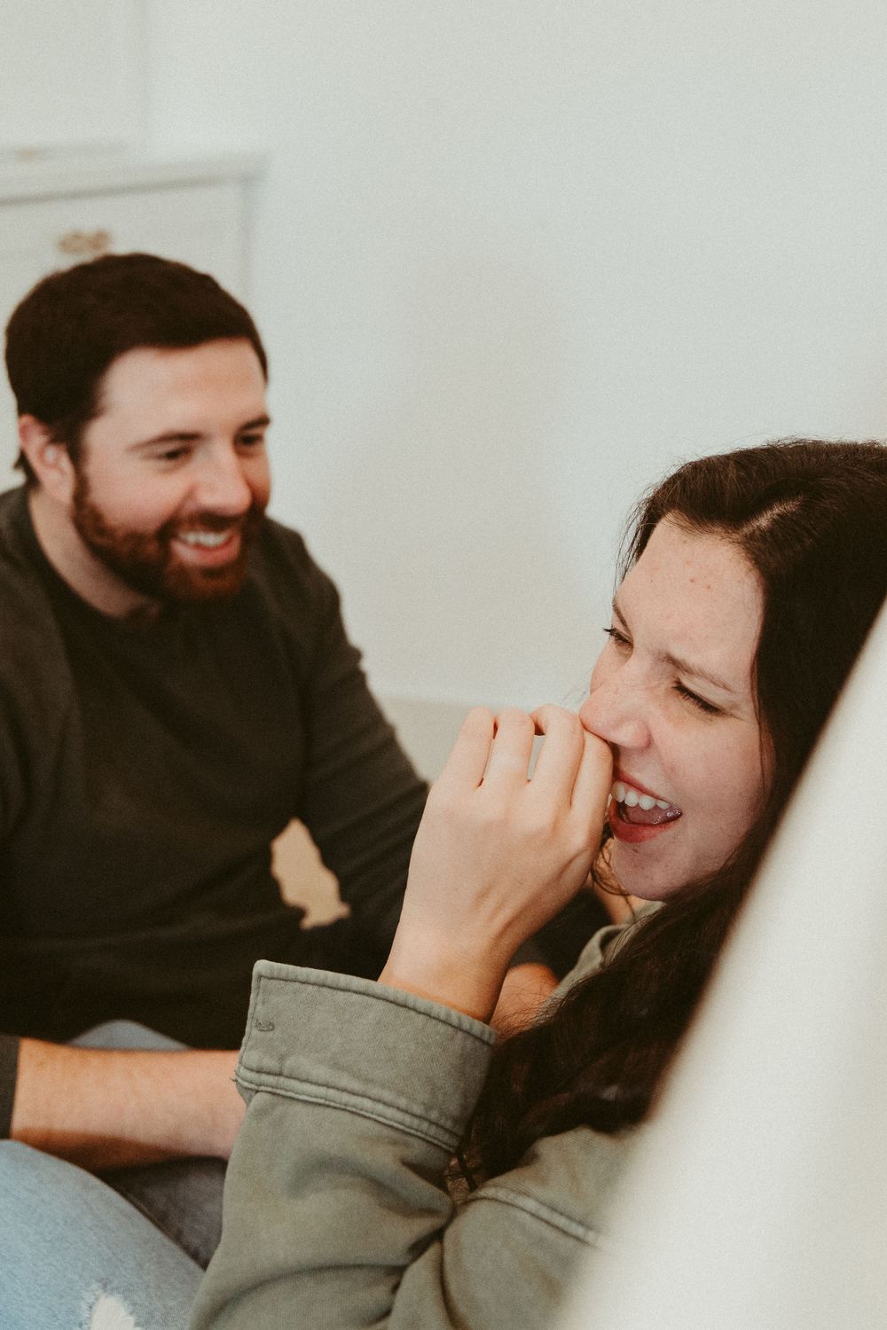 A candid moment of laughter shared between two people in a bright white room.