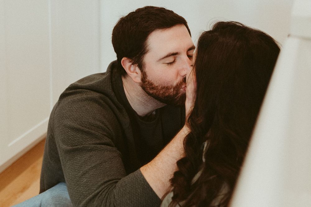 An intimate moment captured between two people in a bright, modern kitchen setting.