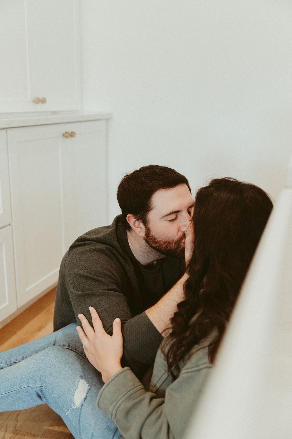 A tender moment shared between two people in a bright, minimalist kitchen space.