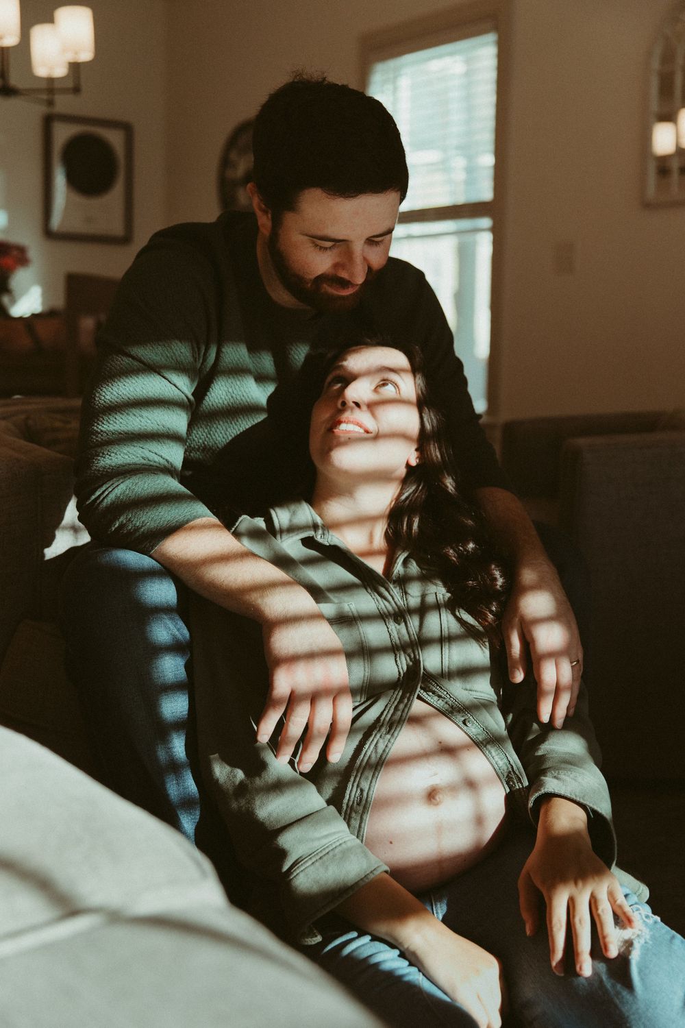 A cozy indoor portrait of two people sharing an intimate moment in window-filtered light.