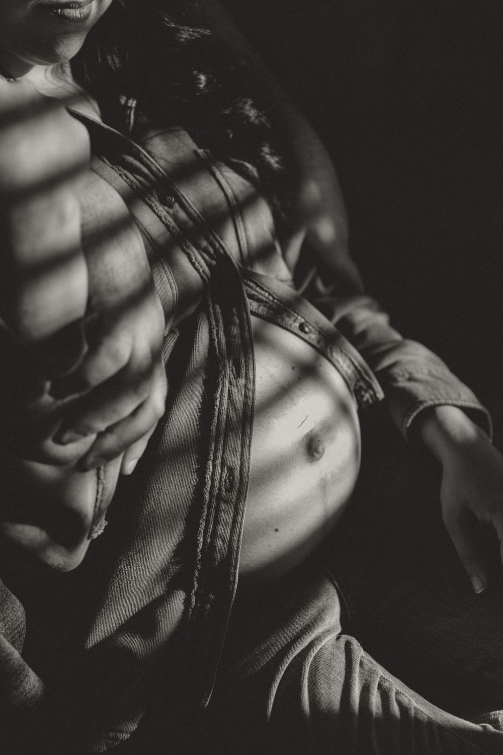 Artistic black and white photo showing torso with dramatic shadows and leather jacket.