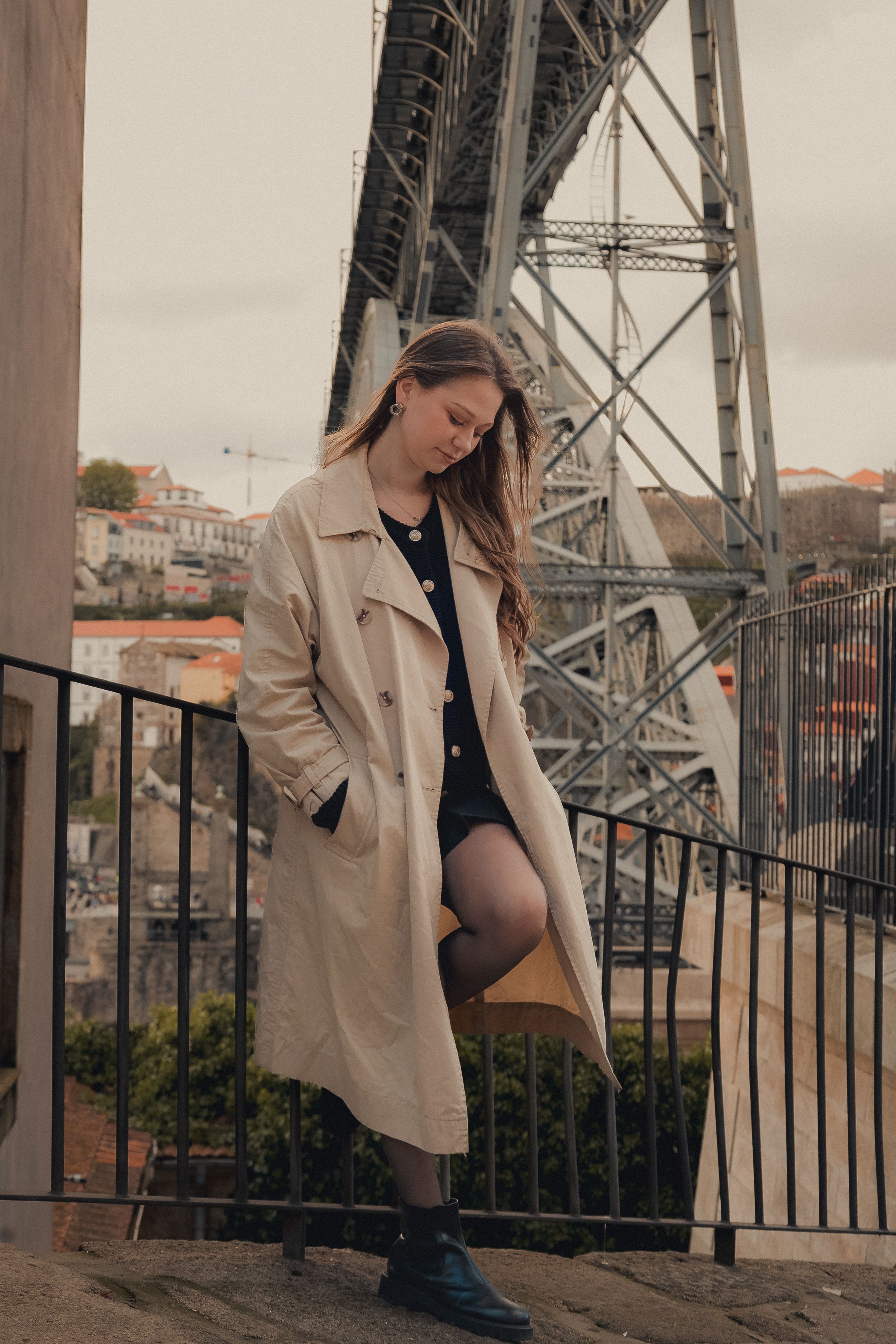 Artistic fashion portraits shot at historic iron bridge with beige jacket and urban backdrop.