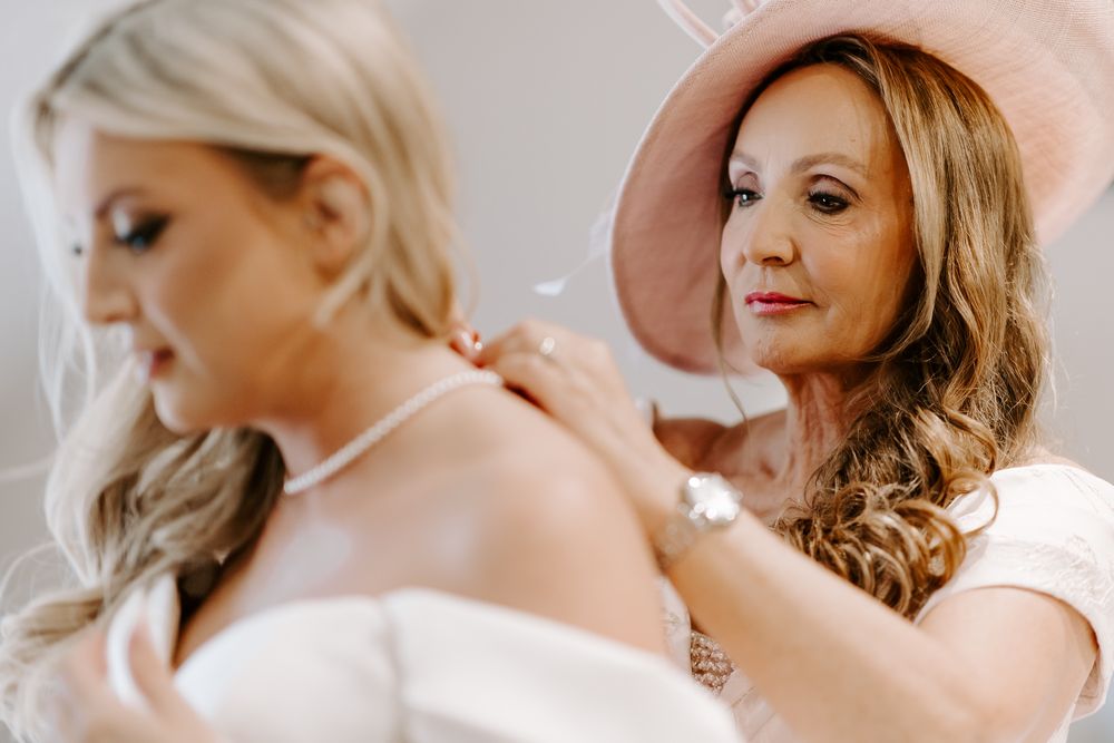 A bride has her makeup professionally applied during wedding preparations as her stylist works carefully on final touches.