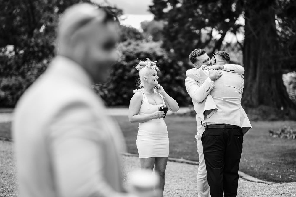 Black and white candid shot of guests taking photos during an outdoor social event.