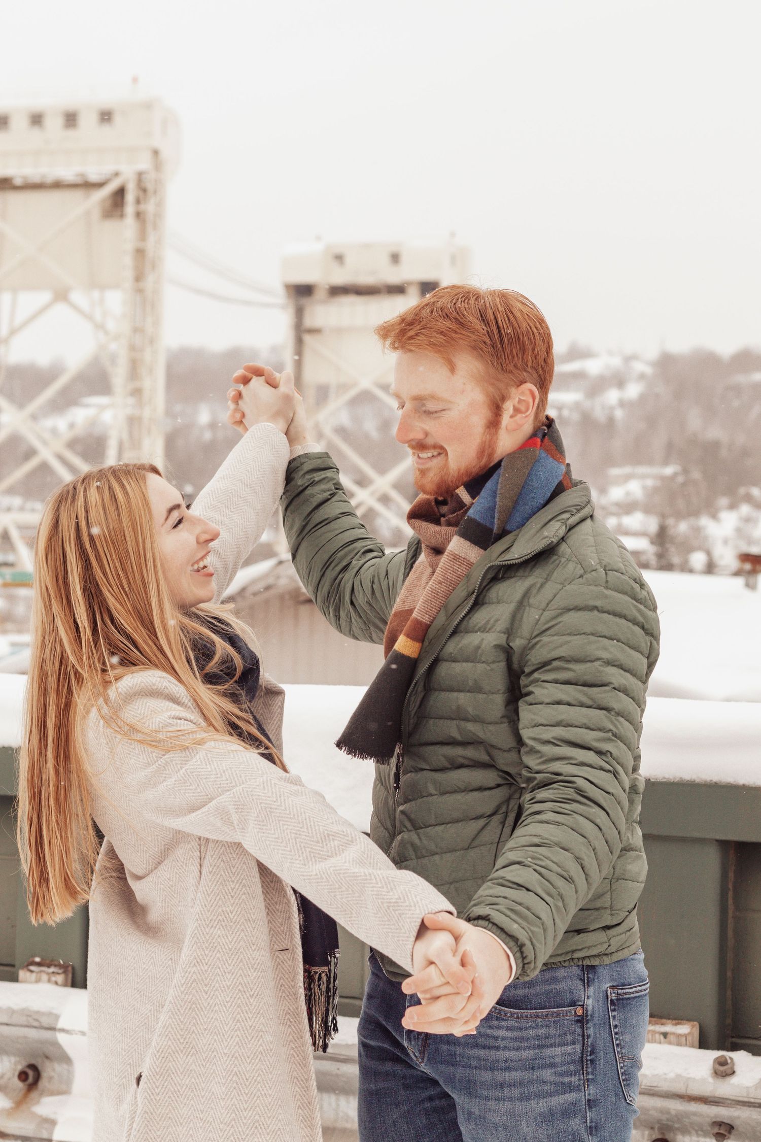 Couple dancing and laughing together overlooking the Houghton-Hancock bridge during winter.