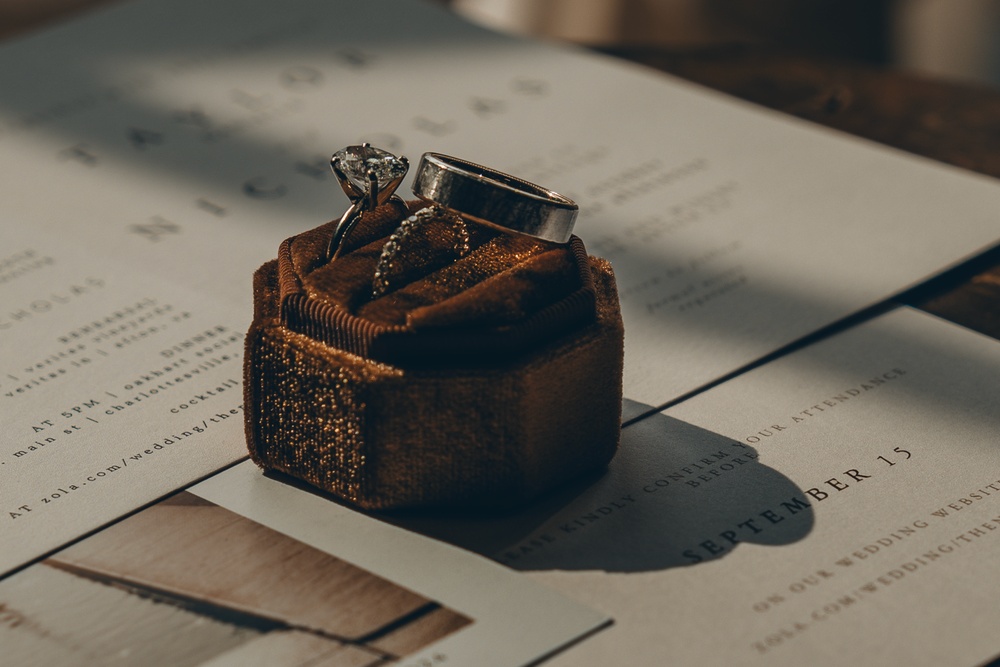 A vintage rusty brown inkwell or ink bottle casting shadows on paper documents in moody lighting.