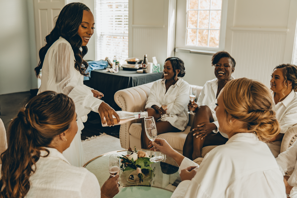 A group of medical professionals in white coats gather around a table for a casual meeting discussion.