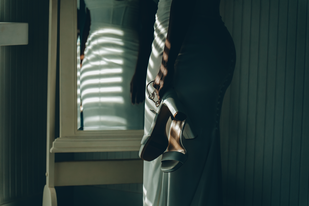 Sunlight casts dramatic striped shadows through window blinds onto a dark wall interior.