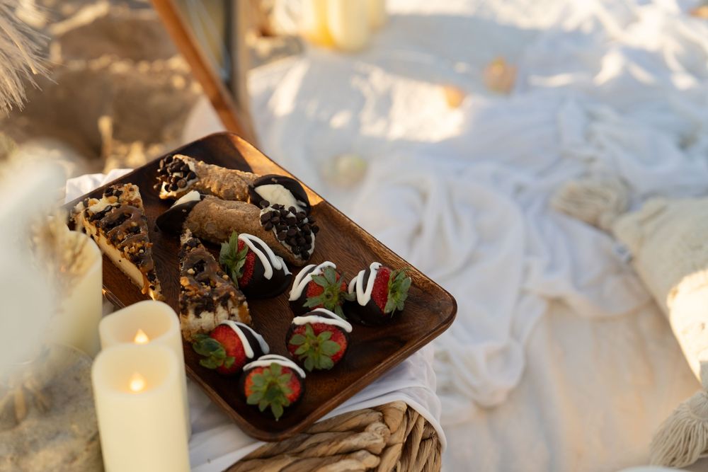 Chocolate covered strawberries arranged on a wooden platter next to glowing candles in a romantic setting.