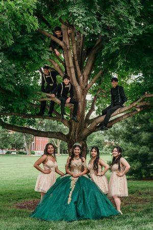 Group photo under tree featuring matching emerald and blush formal attire.