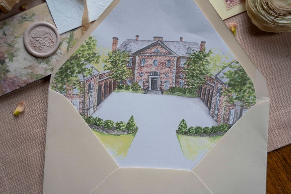 Watercolor paintings of buildings and architecture arranged on a wooden table show architectural artwork in progress.