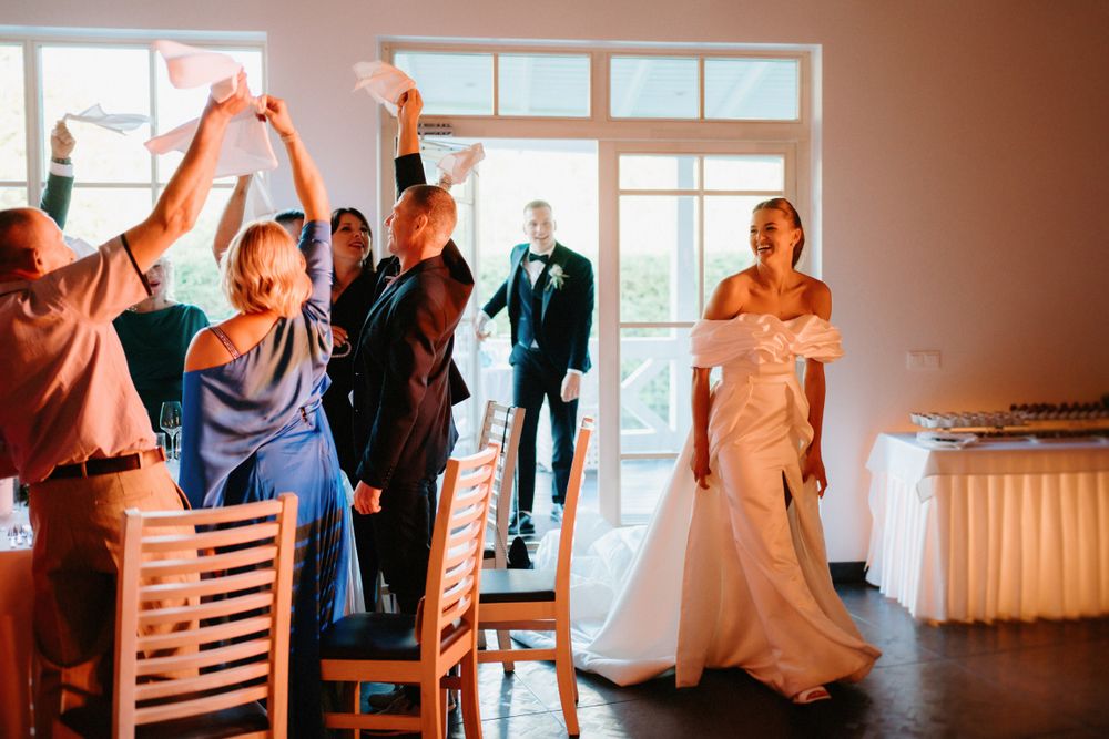 Wedding celebration with guests raising arms in joy during reception.