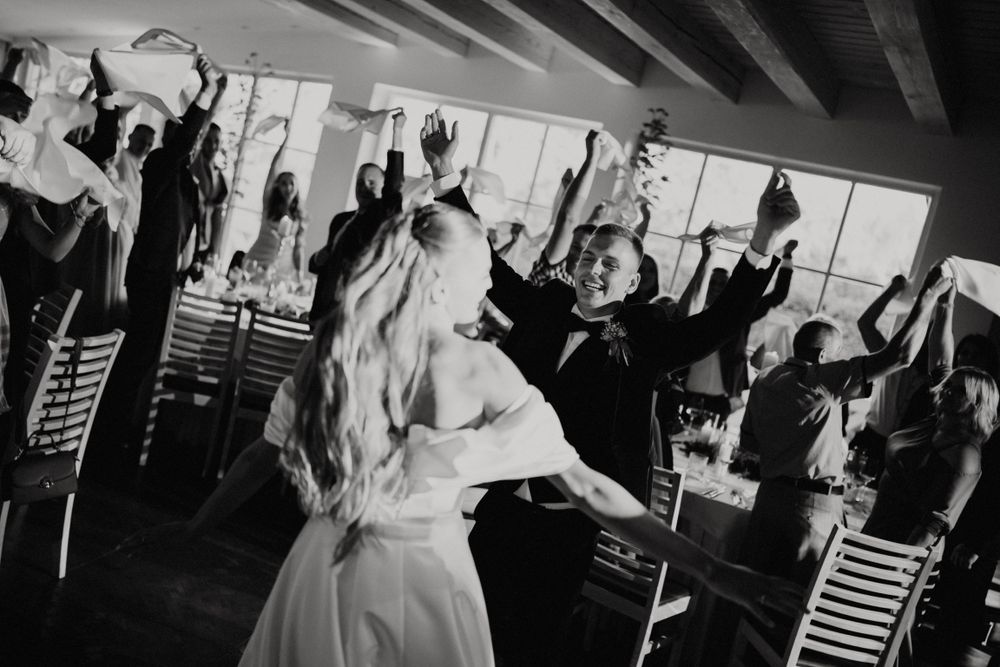 Celebratory scene of wedding guests dancing and cheering in black and white.