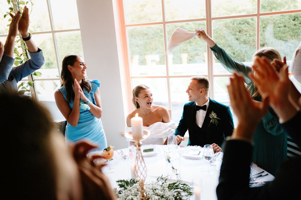 Wedding reception celebration with guests cheering and raising glasses.
