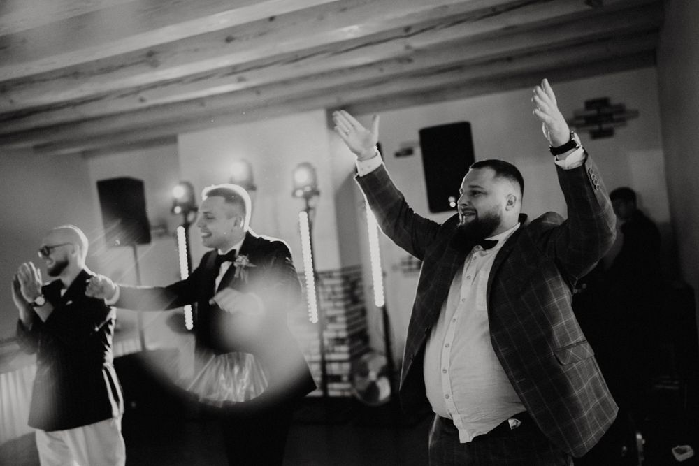 Wedding guests enjoying a lively dance party with colorful lighting and entertainment at an indoor reception.
