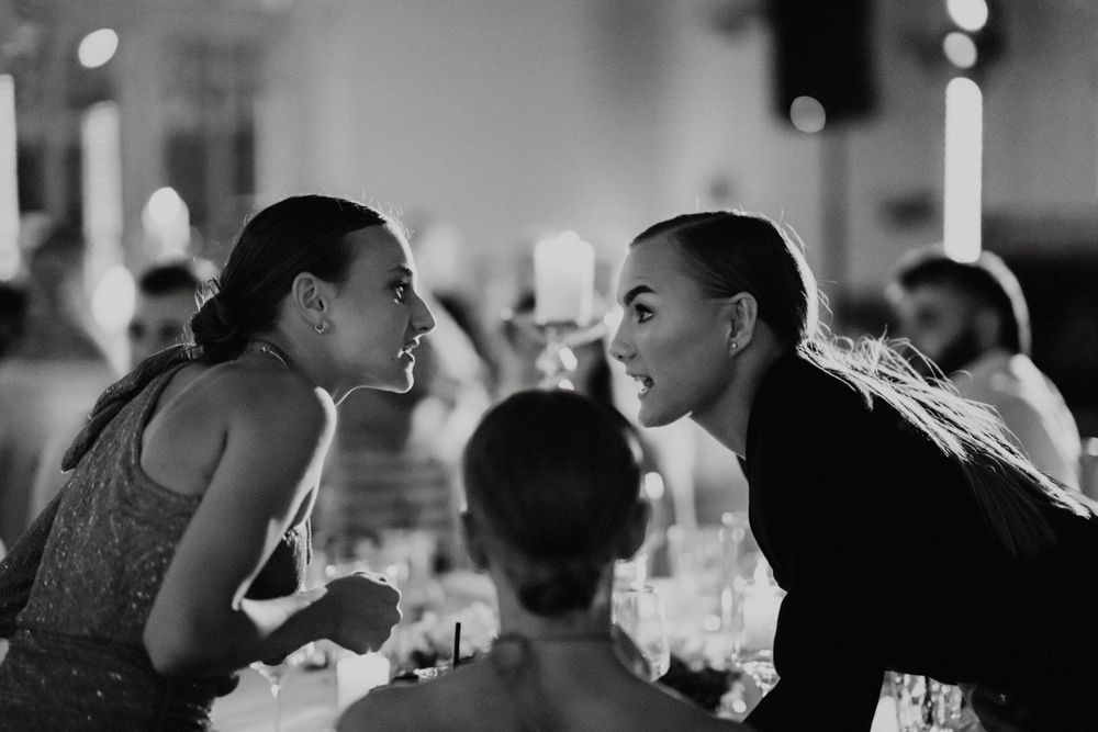 Black and white candid shot of guests mingling and socializing at an elegant reception dinner.