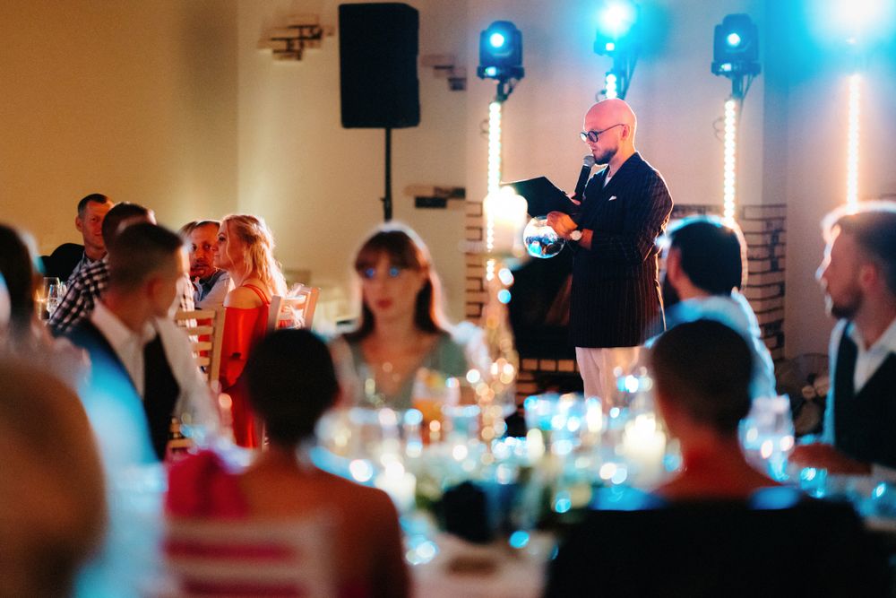 Reception hall filled with guests enjoying entertainment with dramatic blue stage lighting.