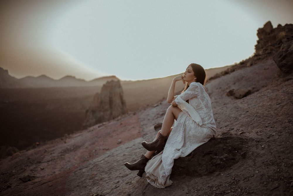 Seven artistic and moody photographs showing a figure in a flowing white dress posing in a desert landscape at sunset.