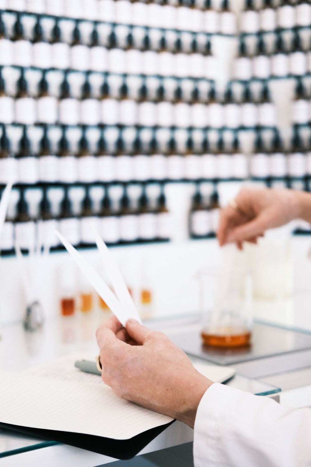 Close-up branding photo of a perfumer testing fragrances in a studio, highlighting artisanal craftsmanship and brand identity visuals.