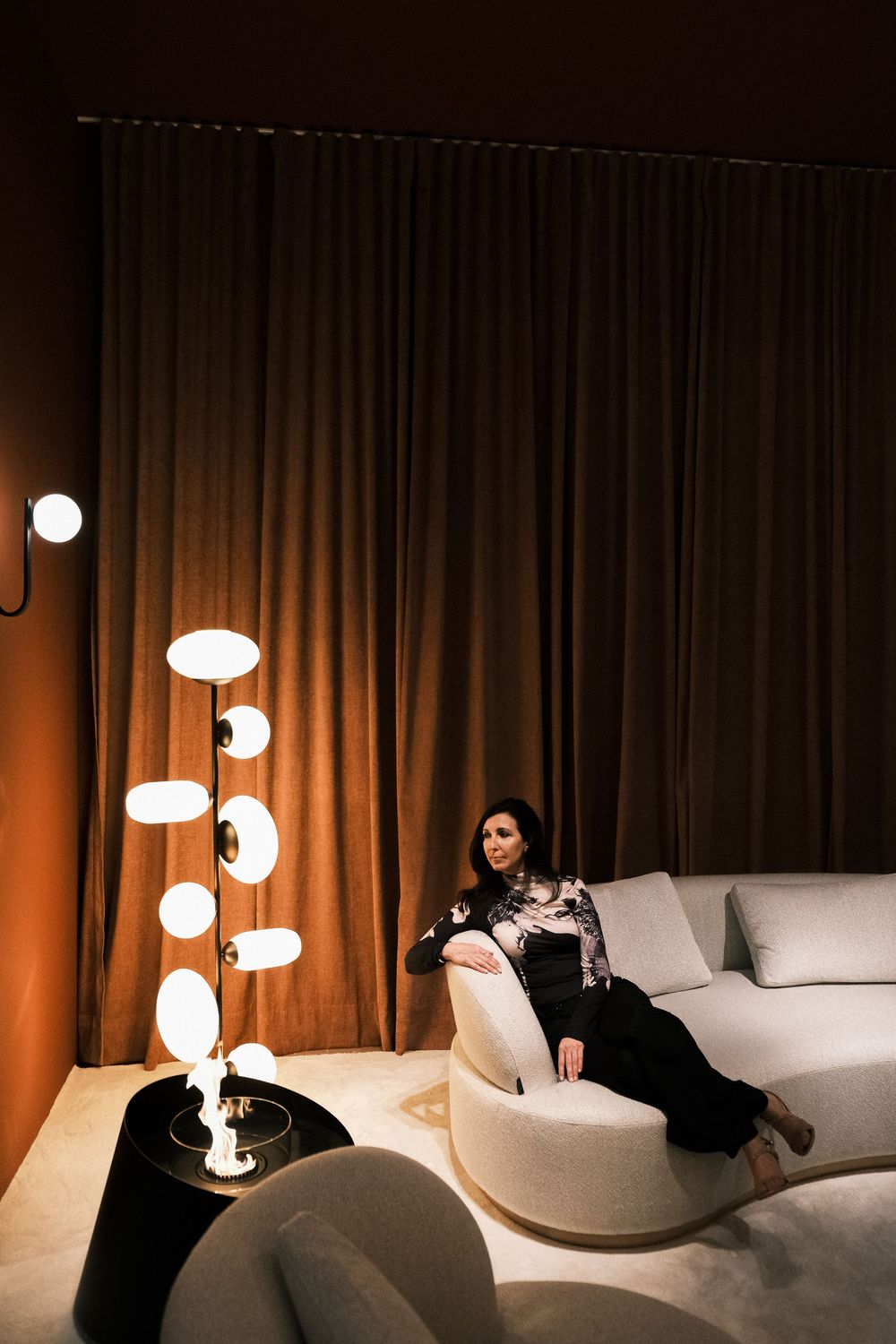 Lifestyle branding photo of a woman seated in a designer interior with sculptural lighting, showcasing modern visual identity photography.