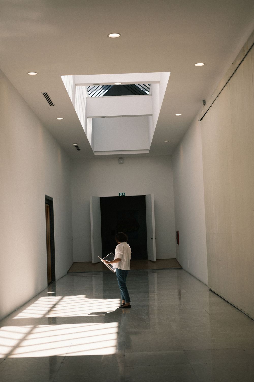 Editorial-style branding photography of a person standing in a modern gallery space with natural light, creative storytelling for brands.