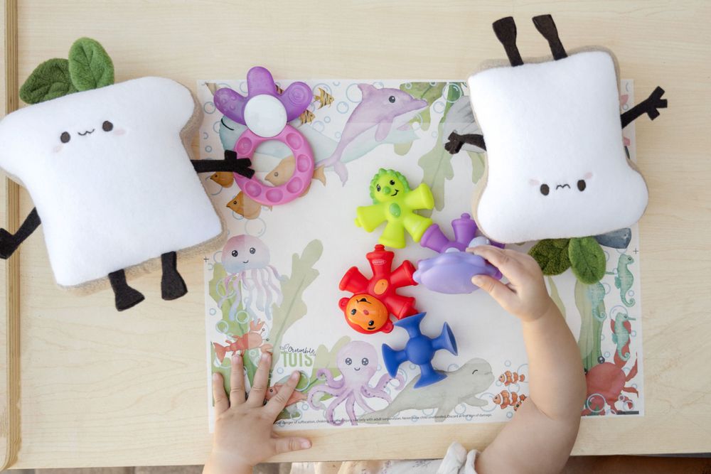 Art activity with white plush characters and colorful flower decorations on a playful mat.