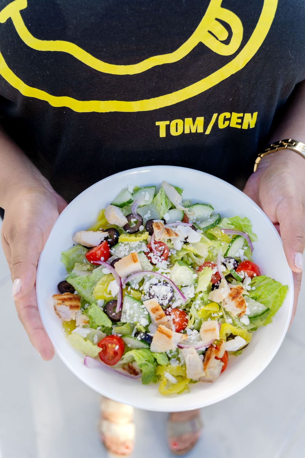 Fresh chopped salad in white bowl with Tom/Cen logo t-shirt visible.
