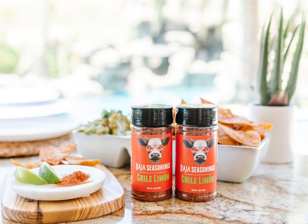 Two bottles of Angry Pig BBQ spice rub displayed with appetizers and wooden serving boards.