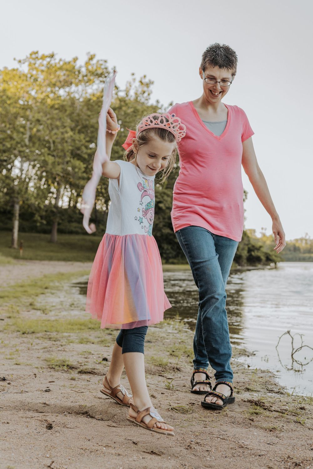 Parent and child walking along beach path with princess costume and wand.