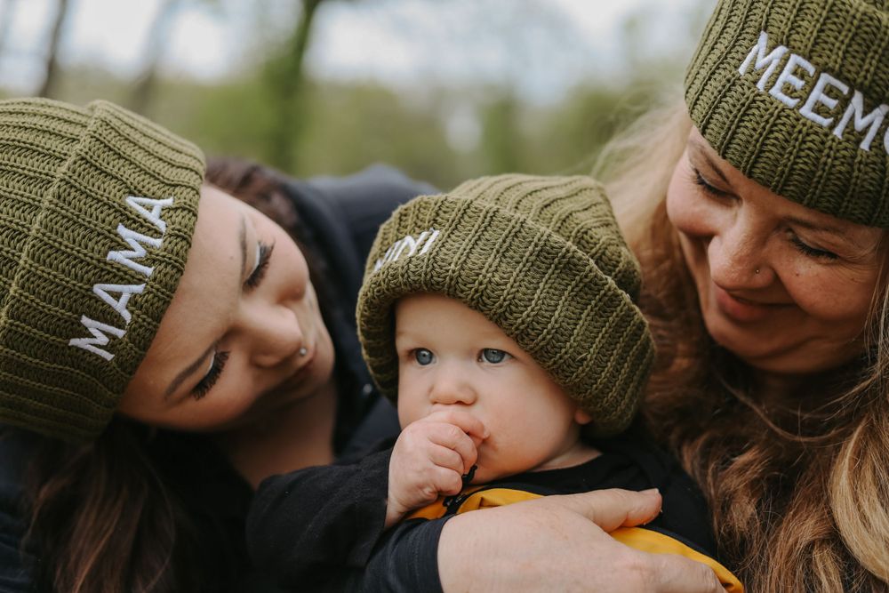 Close-up of family snuggling together in matching olive green knit hats.