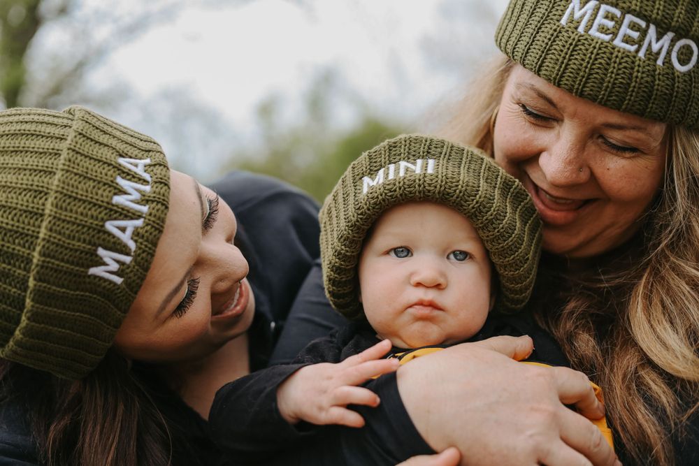 Sweet candid moment of family cuddling together while wearing matching green beanies.