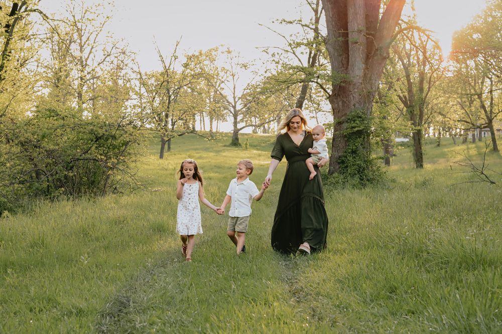 Family walks together through a sun-dappled meadow on a warm afternoon.