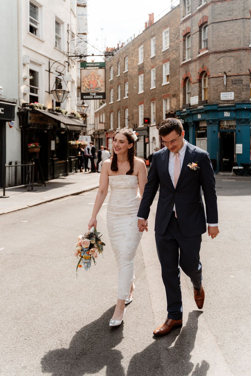 Couple walking hand in hand through historic cobblestone streets.