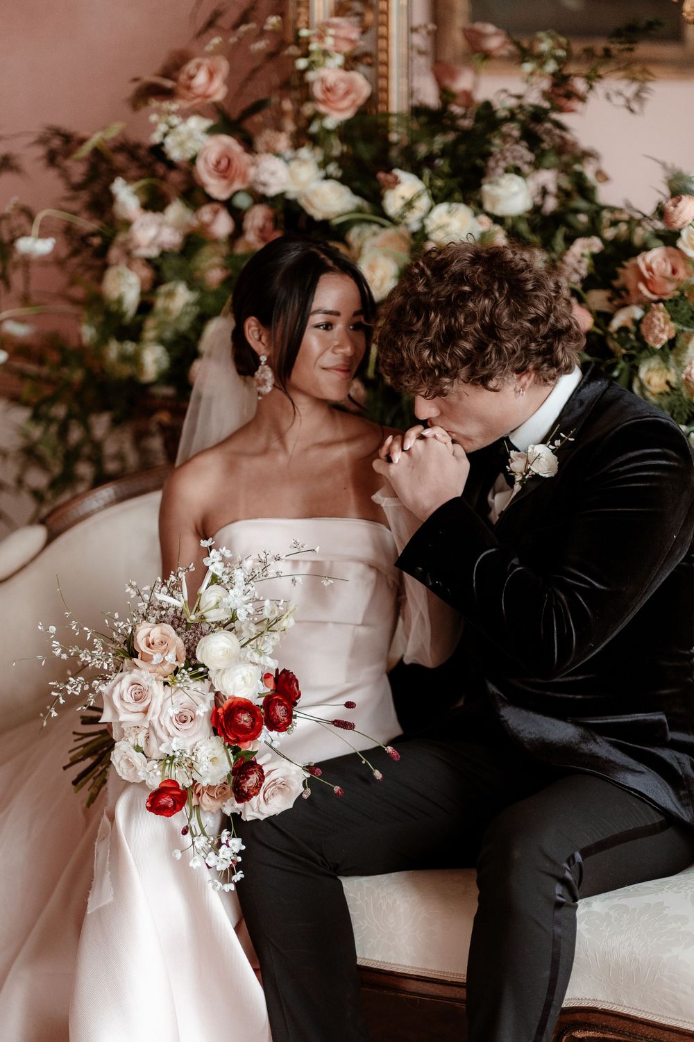 Intimate wedding portrait with luxurious floral backdrop of roses in pink and white.