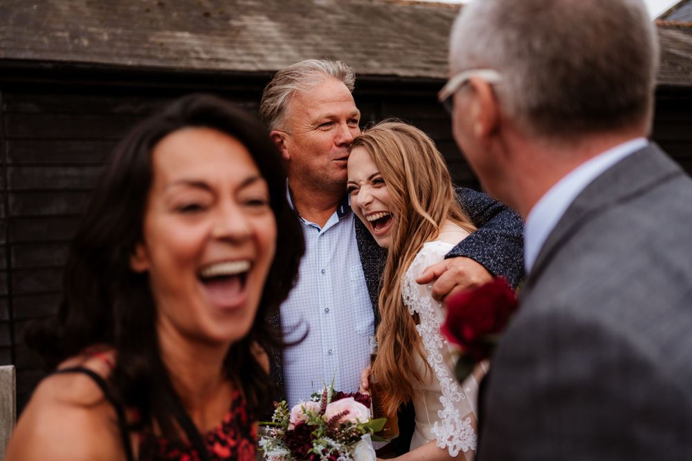 Wedding guests share joyful laughter during an outdoor reception.