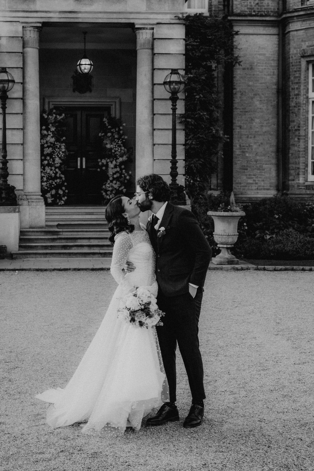 Wedding couple poses outside historic brick building with columns.