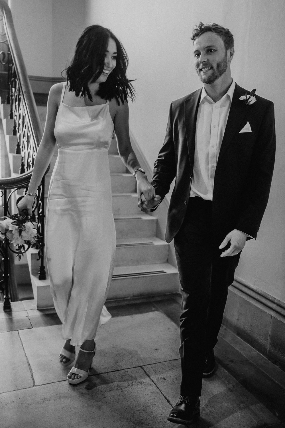 Black and white candid shots of couple walking and laughing together in formal attire.