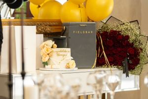 Decorative display featuring yellow balloons, flowers, wine glasses, and a grey Fieldday book on a white mantel.