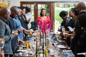 A group gathers around an elegant dining table for a celebratory meal with drinks and conversation.