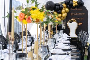 Elegant black and gold party table setting with floral centerpieces and formal place settings for a luxury celebration.