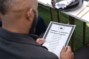 Someone reading a graduation program at an outdoor commencement ceremony.